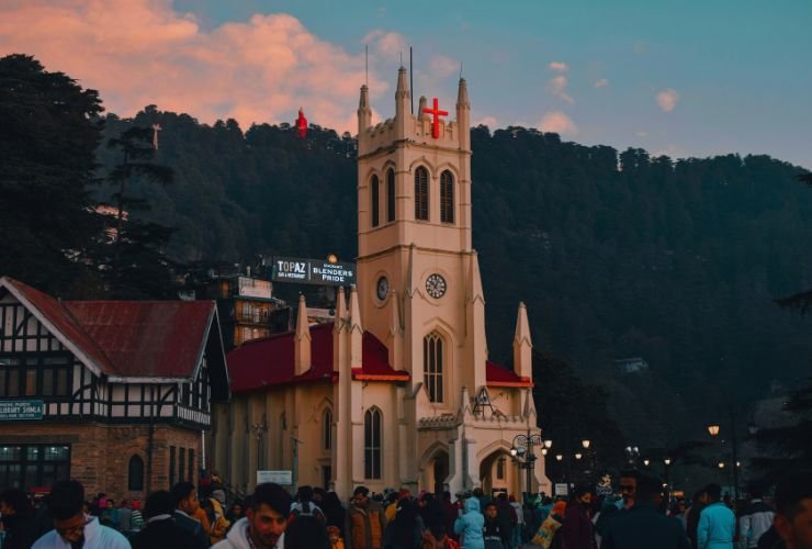Christ Church on Shimla Ridge with clock tower, surrounded by pine-covered hills and tourists, key Shimla tourist place.
