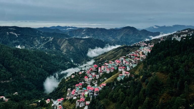 Panoramic view of Shimla tourist places with colorful houses on misty Himalayan hillsides.